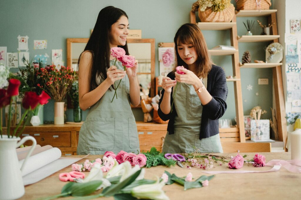 Two female florists arranging flower bouquets in a cozy workshop, creating beautiful floral designs.